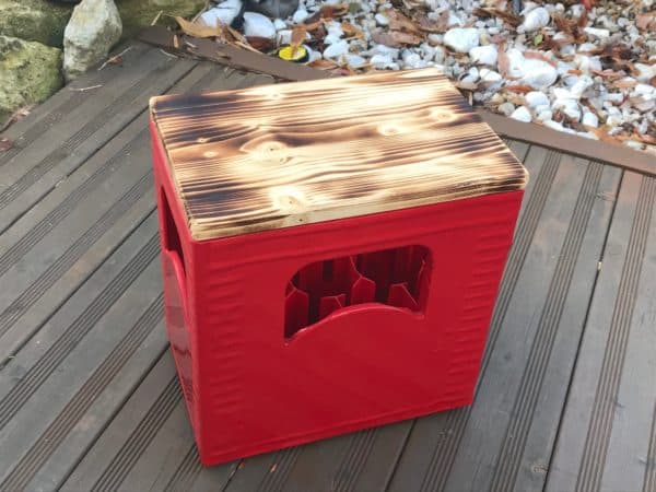 geflammter Bierkastensitz auf rotem Kasten auf Terrassenboden mit Holzverkleidung.